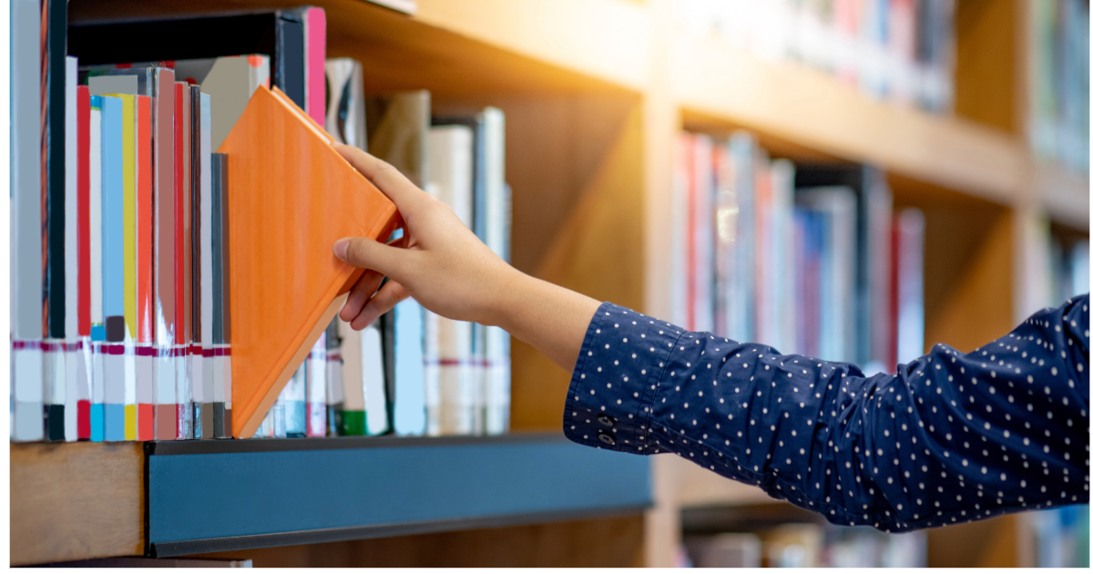 A woman in a polka dot sweater takes a library book off the shelf